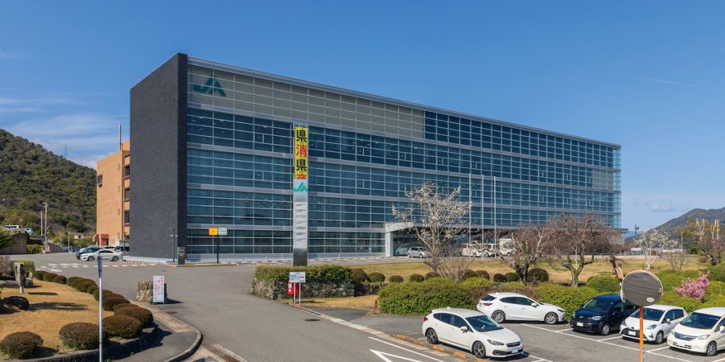 JA影響日本全國各地的農業生產、倉儲到通路，即使稻米通路逐漸多元化，仍在稻米調度扮演重要角色。圖為山口縣JA本部。（攝影╱Yasu on Wikimedia,CC BY-SA 3.0）