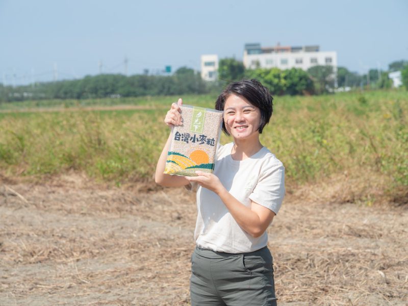 郭慧蟬手拿月光下出品的小麥粒，笑容燦爛。