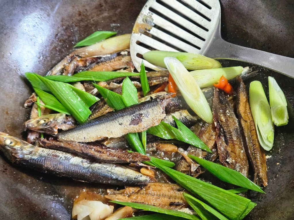 料理步驟
1 用刀背敲開臭肉魚乾的背部,魚頭和魚骨都可以丟棄不用,因我個人喜歡魚內臟的苦味,所以留下來一起煮。蒜苗、蒜頭切片。
2 熱鍋下油,中火爆香蒜頭、魚乾,加入糖、醬油後快速翻炒,炒出醬香就可以加入米酒與水,蓋上鍋蓋,以中火燜煮三分鐘,直到略收汁。再加入已切好的蒜苗辣椒,拌炒均勻就可以盛盤,品嘗海風鹹鹹。