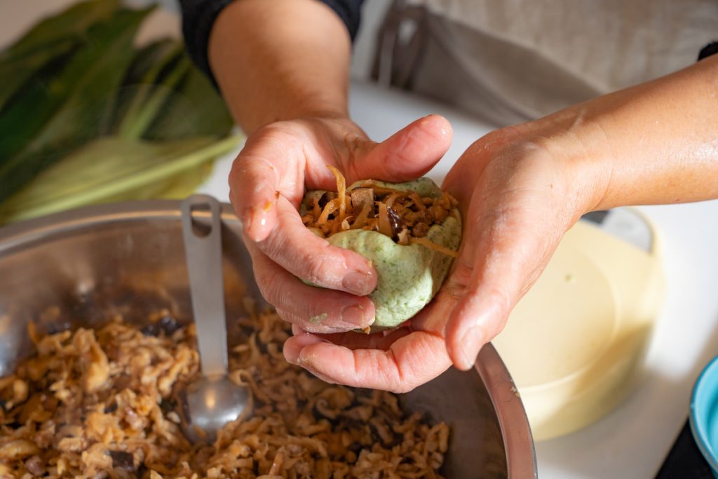 將放涼的餡料包入艾草粄糰中,再小心收緊。