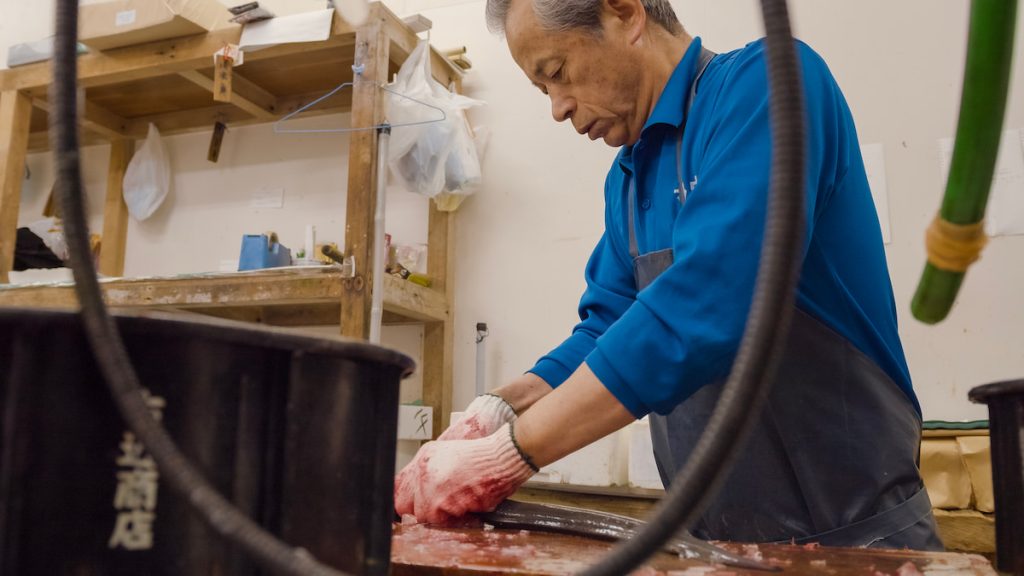 每日魚市場鮮魚拍賣時,副社長輝章在剖鰻魚。