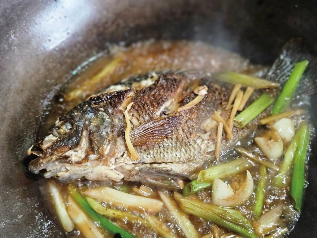 4 不須洗鍋，薑蒜、蔥白先下，加入一匙糖、一大匙醬油，大火炒出醬香，迅速加入一大碗水以免燒焦，把魚放回鍋中，蓋上鍋蓋，中火滾煮五分鐘。
5 魚翻面，加入蔥綠後大火收汁，盛盤享用。
