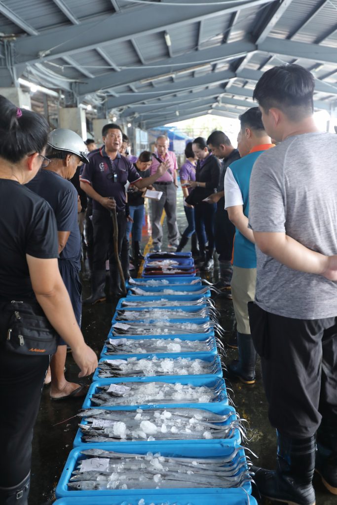 每批魚貨都經「糶手」（拍賣官，中間正面者）喊聲拍出，過程快速且神秘。